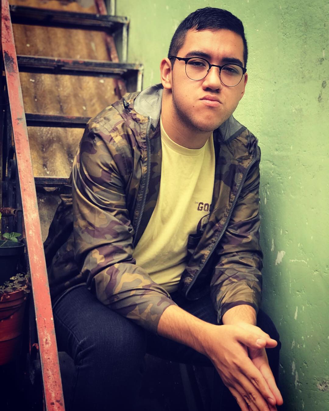 Professional photo of Fernando looking serious while sitting on some stairs.